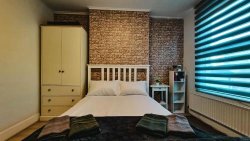 a bedroom with a bed and a brick wall at CityStay London in London