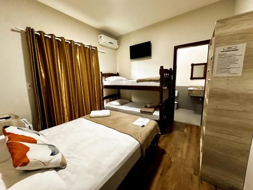 a small room with two beds and a mirror at Pousada Recanto das Cores in Penha