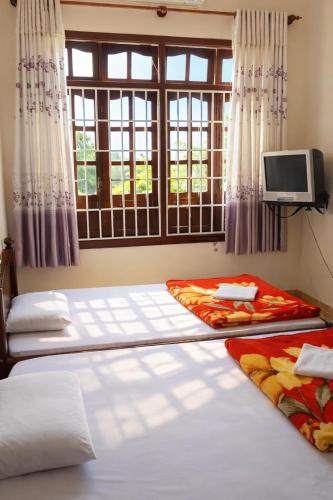 two beds in a room with a window at Tứ Hưng Hotel Bảo Lộc in Bảo Lộc