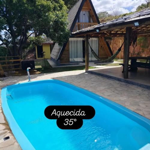 a swimming pool in front of a house at Chalé Bela Vista in Munhoz