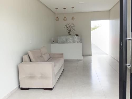 een witte woonkamer met een bank en een tafel bij Pousada Flor de Caroá in Piranhas