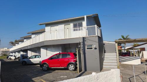 een rode auto geparkeerd voor een gebouw bij Pousada Emanuel in Araranguá