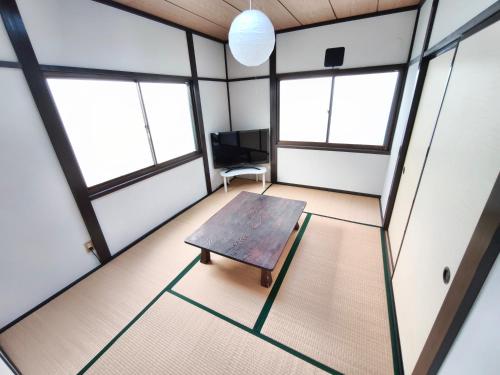 an empty room with a wooden table and two windows at みん民ハウス上浅田 in Hamamatsu