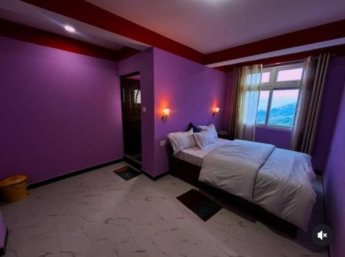 a bedroom with purple walls and a bed with a window at Tashidelk homestay in Darjeeling