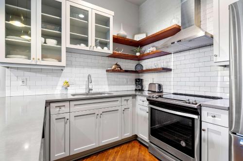 a kitchen with white cabinets and a sink and a stove at Perfect Location - King Street Condo in Charleston