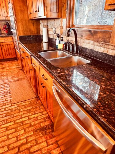 a kitchen with a stainless steel sink and wooden cabinets at The Royal Chateau-5BED6BATHPoolHottub-20PP in Osage Beach