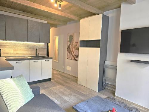 a kitchen with white cabinets and a tv on the wall at Moda Apartments 47 in Sestriere