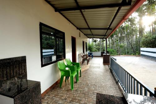 a porch with green chairs on a house at Areca Nut Homestay in Mudigere
