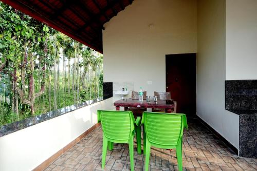 two green chairs sitting next to a table on a patio at Areca Nut Homestay in Mudigere