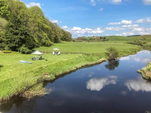 a view of a river with a tent and a field at Harperfield Chalet in Lanark
