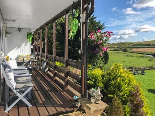 a deck with chairs and flowers on a house at Harperfield Chalet in Lanark