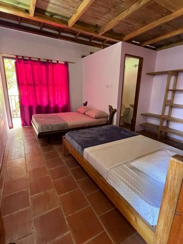 two beds in a room with red curtains at Suelo Vivo Eco Hotel in Bochalema