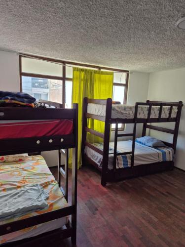 een kamer met 3 stapelbedden en een raam bij Charlotte House in Huanchaco