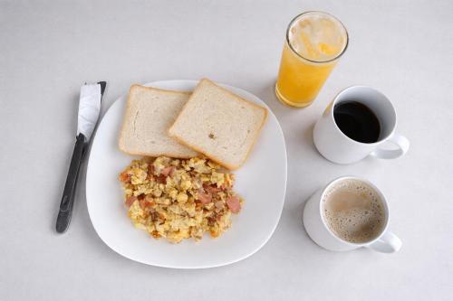 een bord met eten, toast, koffie en een glas sinaasappelsap bij HOTEL NES in Maicao