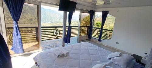 a bedroom with a large bed and large windows at Supernova Glamping in Macanal