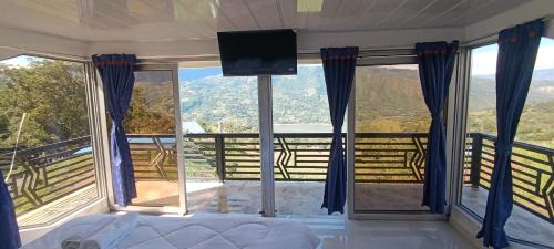 een slaapkamer met een bed, een tv en ramen bij Supernova Glamping in Macanal