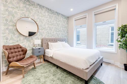 ein Schlafzimmer mit einem Bett, einem Spiegel und einem Stuhl in der Unterkunft Mont Royal Suites - M11 in Montreal