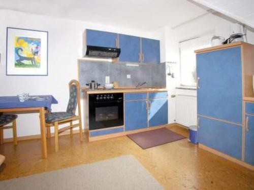 a kitchen with blue cabinets and a table and a stove at Apartment FEWO Veilchen by Interhome in Ernst