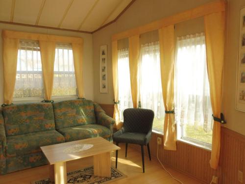 a living room with a couch and a chair and windows at Holiday Home mit Pool by Interhome in Radewege