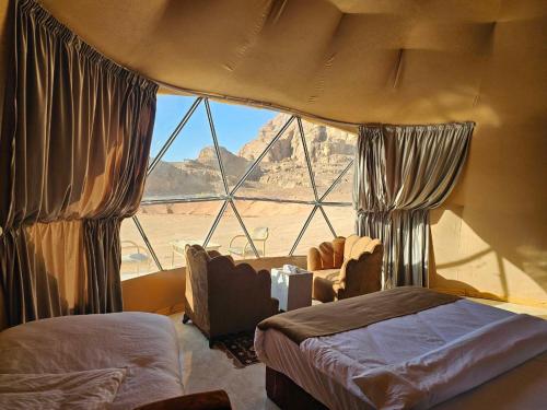 een slaapkamer met een groot raam met uitzicht op de woestijn bij Wadi Rum Luxury Camp in Wadi Rum