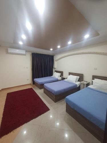a hotel room with two beds and a red rug at SARAYA AWAD HEGAZI STREET- families only in Alexandria