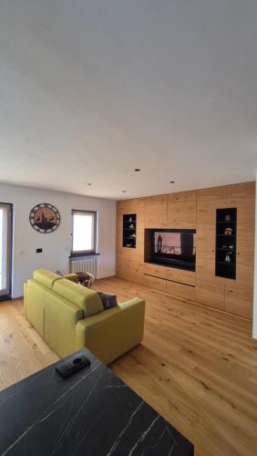 een woonkamer met een gele bank en een televisie bij La Trementina Apartment & Spa in Dimaro