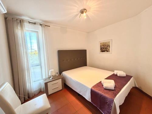 a bedroom with a bed and a table and a window at Algardia Marina Parque by Garvetur in Vilamoura