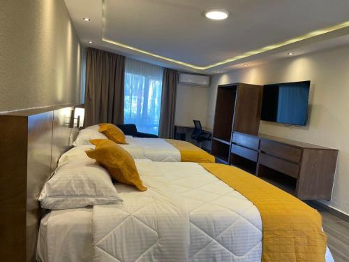a hotel room with two beds and a television at Hotel Imperial Saltillo in Saltillo