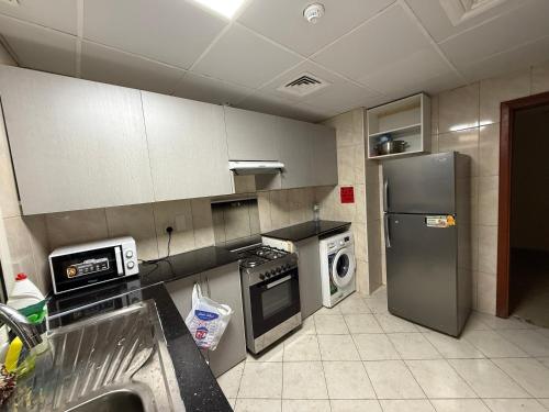 a kitchen with a refrigerator and a dishwasher at Cozy Room with shared 2 whasroom Rashdiya 1 Ajman in Ajman