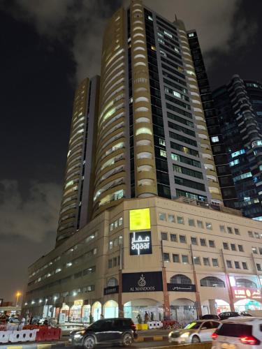 a large building with cars parked in front of it at Cozy Room with shared 2 whasroom Rashdiya 1 Ajman in Ajman