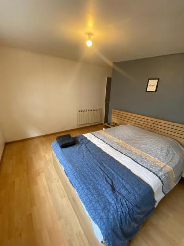 een slaapkamer met een bed met een blauw dekbed bij Le Glatigny in Le Havre