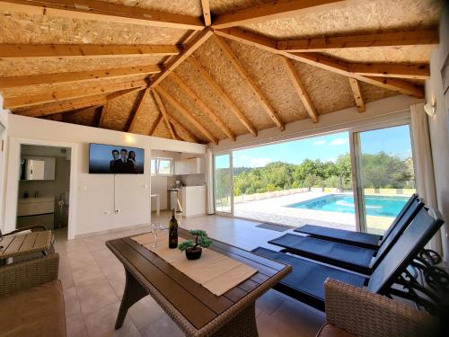een woonkamer met een tafel en een zwembad bij Villa Gorana for 10 with large private pool in Sutina