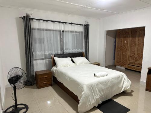 een slaapkamer met een groot bed en een raam bij The 12th Avenue in Lusaka
