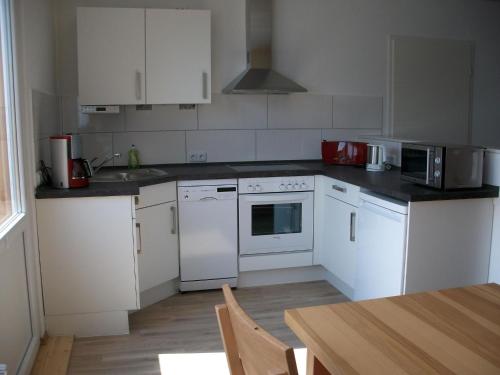 a kitchen with white appliances and a wooden table at Apartment Fewo Edison by Interhome in Holzdorf