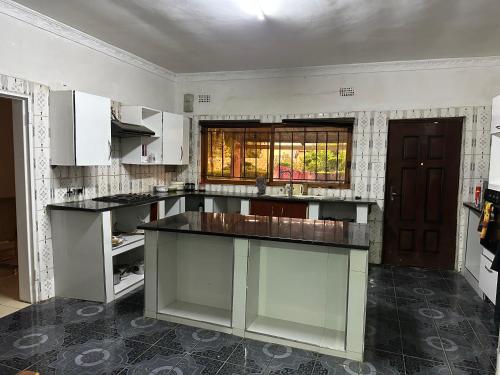 een grote keuken met witte kasten en een raam bij The 12th Avenue in Lusaka