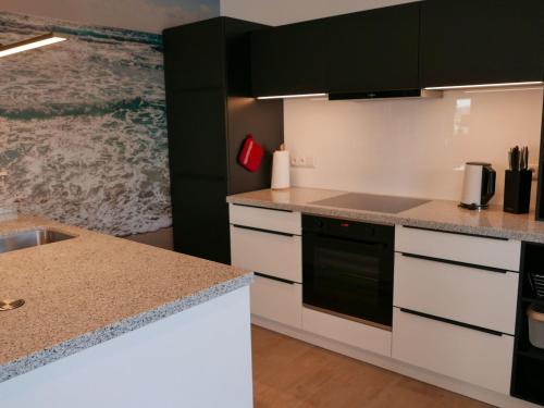 a kitchen with white cabinets and black appliances at Holiday Home Knut by Interhome in Mellnitz