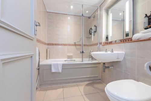 a bathroom with a tub and a sink and a toilet at Winchester Wessex Hotel by Sunday in Winchester