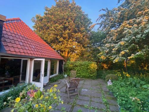 a patio with two chairs and a red roof at Achter de kerk in Eppenhuizen
