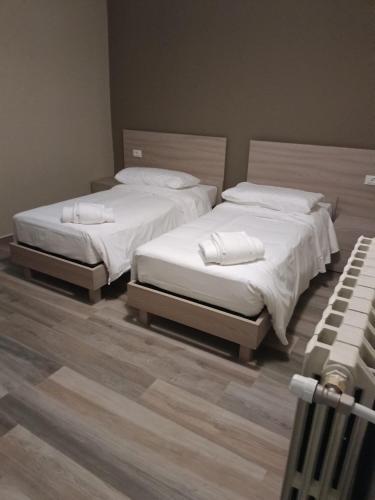 2 aparte bedden in een kamer met houten vloeren bij OSTERIA IL BECCO FINO affittacamere in Cumignano sul Naviglio