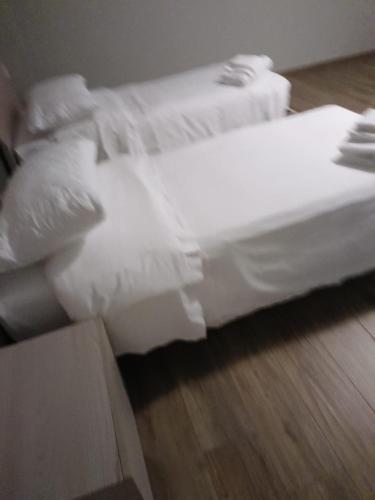 twee bedden met witte lakens op een houten vloer bij OSTERIA IL BECCO FINO affittacamere in Cumignano sul Naviglio