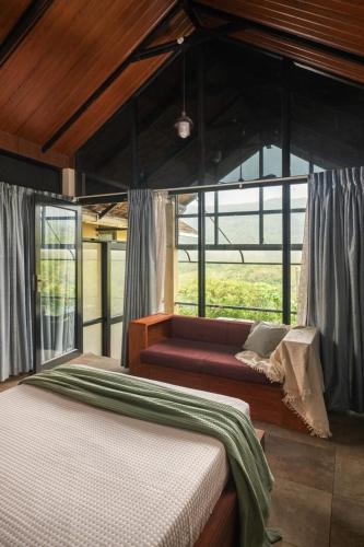 a bed and a couch in a room with windows at Kood Heritage cottages in Vagamon