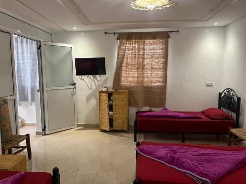 a room with two beds and a refrigerator at Taghazout surf in Tamraght Ouzdar