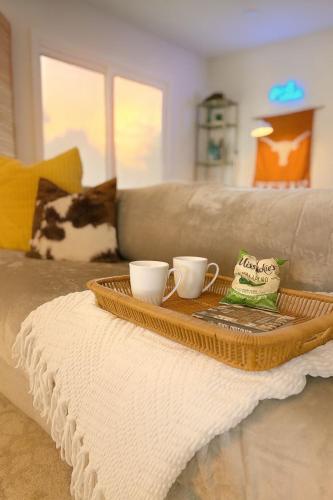 a tray with two coffee cups on top of a couch at Longhorn Pool Home with King Bed & Rain Showers Walk to DT & Lake in Austin