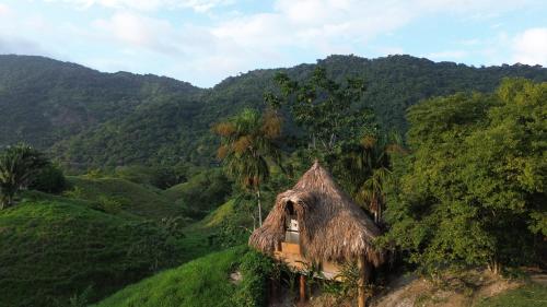 een kleine hut op een heuvel in een vallei bij The Valley Tayrona hostel- A social jungle hostel in El Zaino