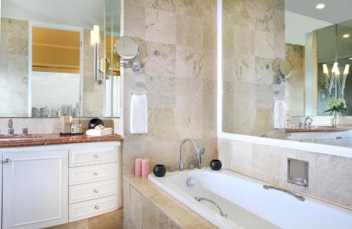 a bathroom with a tub and a large mirror at Ascott Jakarta in Jakarta