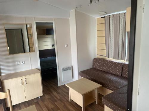 ein kleines Wohnzimmer mit einer Couch und einem Tisch in der Unterkunft Charmant Mobilhome in Lagrand