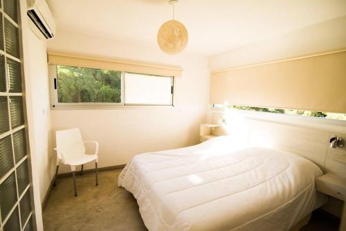 a bedroom with a white bed and a window at Samay Huasi - Cabañas y Casa de Te in Chapadmalal