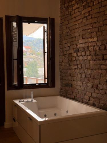 a bath tub in a bathroom with a brick wall at Aprosmeno House 7 in Agros