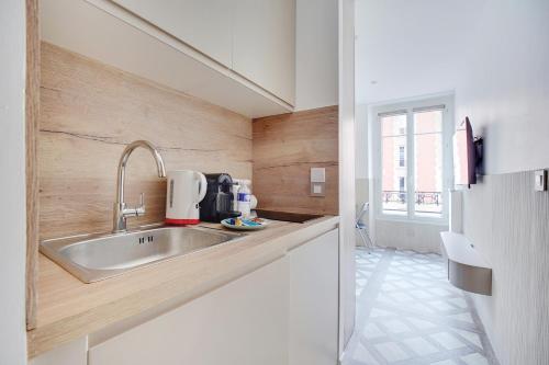 een keuken met een roestvrijstalen wastafel en houten wanden bij Studio cosy - 2P - Bercy in Parijs