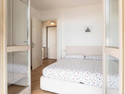 a white bedroom with a bed and a mirror at Apartment 'Cezanne by Interhome in Parzanica